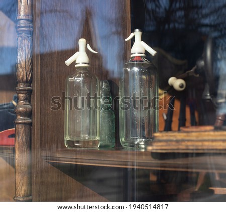 Old-fashioned siphons or bottles in a window of a shop, cafe or restaurant on wooden background. Life of old objects. Home stuff from the past. Vintage decorative elements. Stock photography.