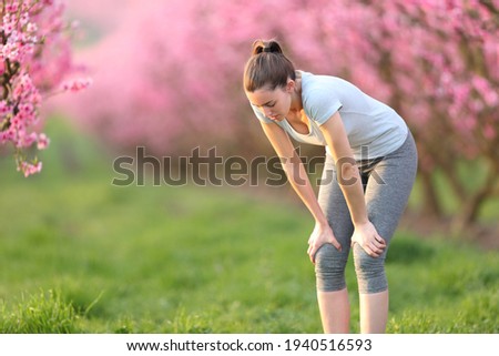 Exhausted runner woman resting after run outdoors in a pink field Royalty-Free Stock Photo #1940516593