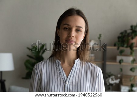 Head shot portrait confident attractive young woman standing at home, looking at camera, businesswoman posing for profile picture, popular blogger influencer shooting video for social network