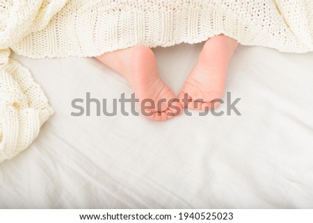 Feet of sleeping child in bed. Sweet baby part covered with soft blanket