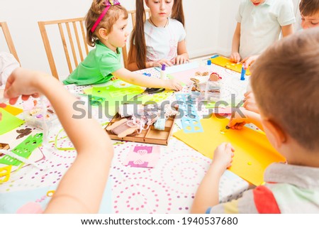 Boys and girls sit around the table and make handicrafts
