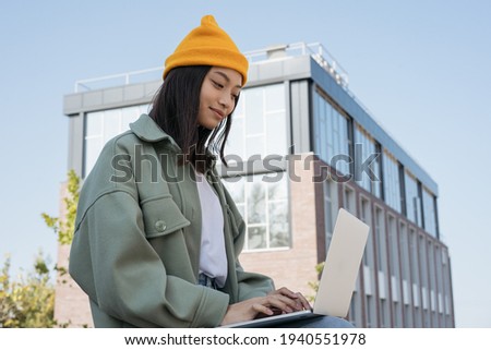 Asian woman using laptop computer, searching online. Young copywriter typing, working freelance project outdoors. University student studying, learning, online education concept 