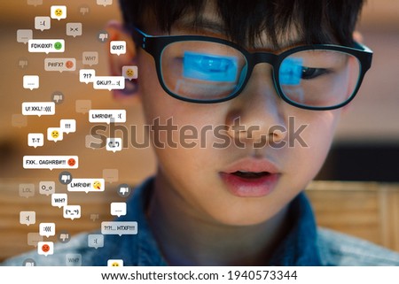 Cyberbullying - social media harassment concept. Close up of   a preteen, teenager boy's face with glasses reflection of computer screen, he feeling stress reading bully comments, Teen mental health. Royalty-Free Stock Photo #1940573344
