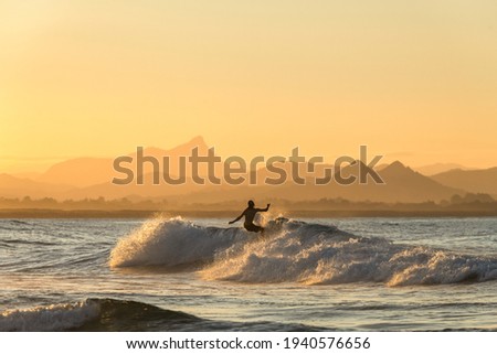 Surfing  at sunset, Byron Bay Australia Royalty-Free Stock Photo #1940576656