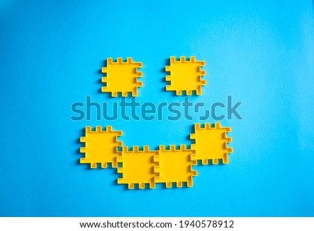 Smile out of puzzles. Smiley made of building blocks on a blue background. Positive concept. Fighting with depresion. Making yourself or someone happy.