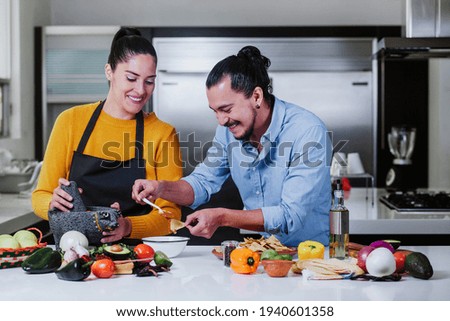 latin couple cooking mexican sauce together in their kitchen at home in Mexico city