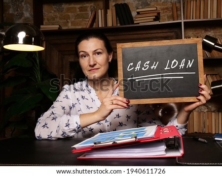 Young woman holding a black chalkboard in hands. Conceptual photo about CASH LOAN with written text. 

