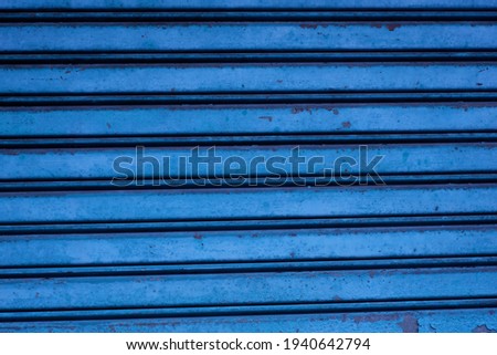 Rolling door is blue. In some parts it has started to rust. This image is suitable for wallpaper or background.