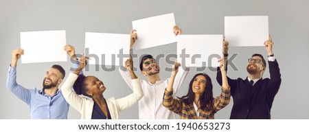 Banner with group of five happy smiling diverse people, colleagues or friends, expressing opinion and giving positive feedback holding white mockup signs and sheets of paper on gray studio background