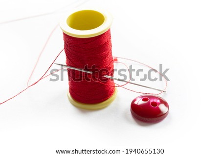 Button with two holes. Thin red thread.