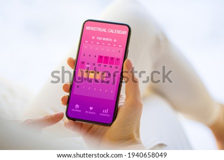 Woman tracking periods by using menstrual calendar app on phone Royalty-Free Stock Photo #1940658049