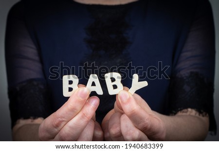 BABY. Word from white letters of wooden alphabet in woman's hand.
