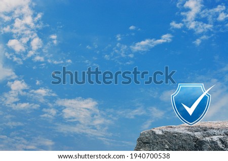 Security shield with check mark flat icon on rock mountain over blue sky with white clouds, Technology internet cyber security and anti virus concept