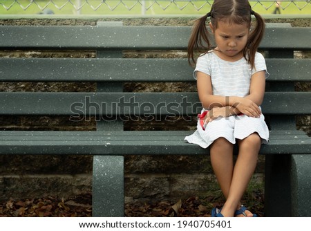 A depressed sad frustrated little girl sitting alone. Social anxiety and stressed children. Royalty-Free Stock Photo #1940705401