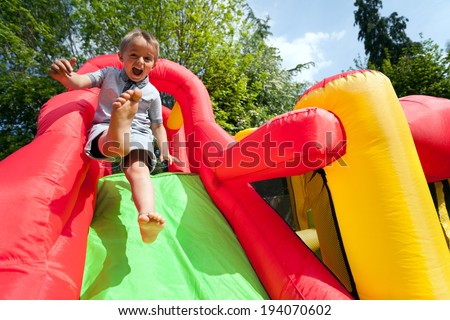 Small boy jumping down the slide on an inflatable bouncy castle Royalty-Free Stock Photo #194070602