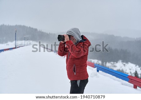 Photographer with camera in the blizzard in the mountains