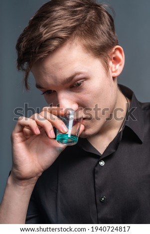 Guy drinks whiskey from a glass on a gray background