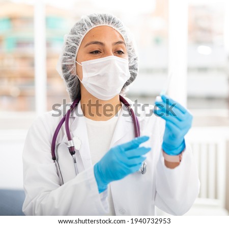 Experienced female health worker working in the clinic prepares a syringe for injection in the treatment room. Close-up ..portrait