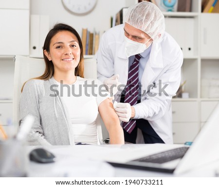 Doctor giving Covid-19 or flu antivirus vaccine shot to patient wear face mask protection at medical office Royalty-Free Stock Photo #1940733211