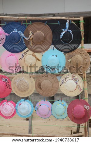 Various types of hats are neatly arranged by hanging on a wooden frame.