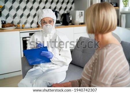 Medical worker in protective workwear visits a senior at home