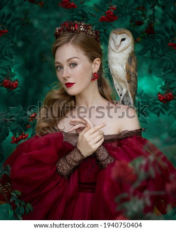 Art photo of a woman in a red dress with a barn owl on her shoulder