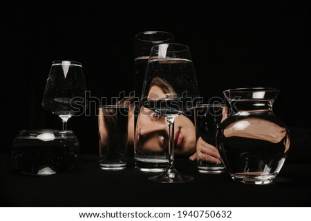surreal portrait of a strange man looking through glasses of water