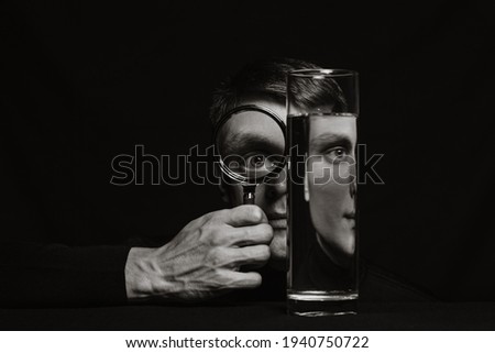 portrait of a man through a magnifying glass and a container of water