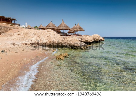 Beautiful sandy beach with rocks and sun umbrellas in Red Sea, Egypt,  Africa.