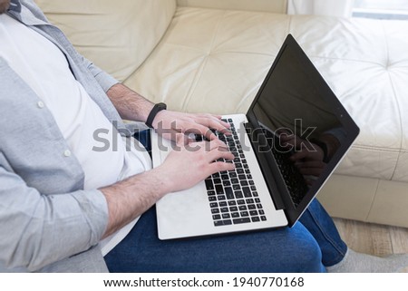 respectable handsome man working from home office, sitting on sofa with laptop, and solving business case