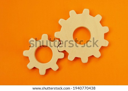 Two wooden gears of different sizes on a bright colored background. Royalty-Free Stock Photo #1940770438