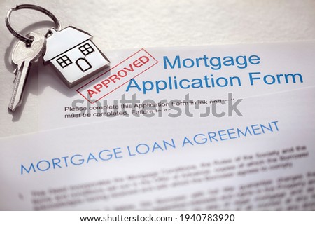 Mortgage application form and loan agreement with  key on house shaped keyring