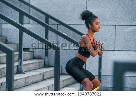 Stretching day. Young african american woman in sportive clothes have workout outdoors.