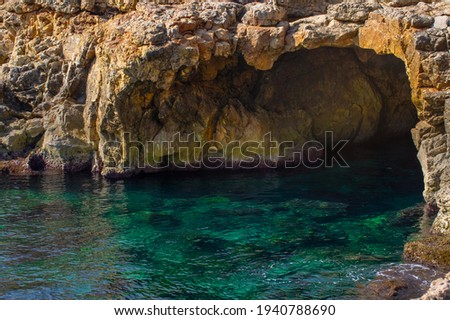 Sea cave, old waterfront below Sliema town in Malta island. Beautiful blue mediterranean sea. Selective focus.