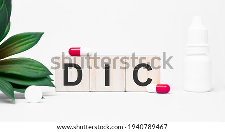 DIC the word is written on wooden cubes,plant and red pills,on white background Royalty-Free Stock Photo #1940789467
