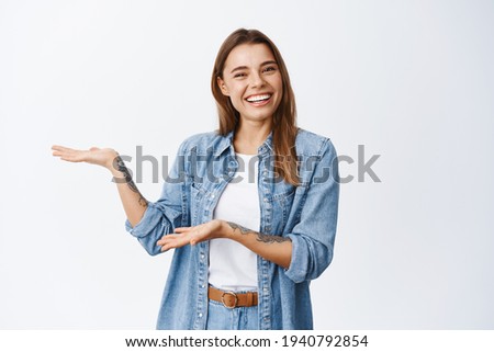 Introducing product to you. Smiling young woman demonstrating an advertisement on white copy space, presenting somethin for client, standing against white background