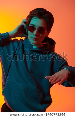 Emotional boy teenager listens to music with headphones and enjoys. Youth culture. Studio portrait in mixed color light. 