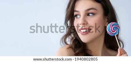 Beauty banner. Skin care. Aesthetic cosmetology. Cheerful curious woman with flawless face white toothy smile colorful lollipop looking at copy space isolated on light advertising background.
