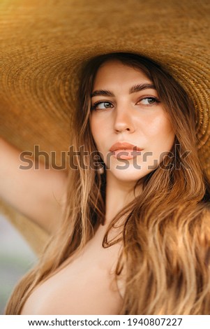 Gorgeous young woman in a big straw hat with long blond hair in a lavender field at sunset. High quality photo