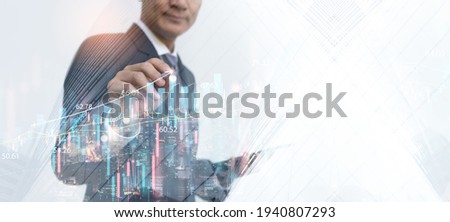 Asian businessman using tablet analyzing marketing report, business data with financial graph, economic growth, development chart with modern buildings. Business strategy and technology concept.
