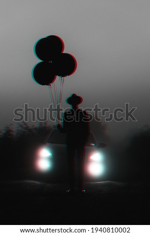 dark silhouette of a man in a hat with balloons in his hand