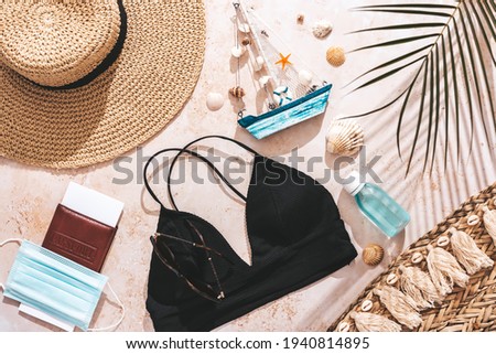 Travel flat lay with passport, clothes, beach accessories, mask and hands sanitizer