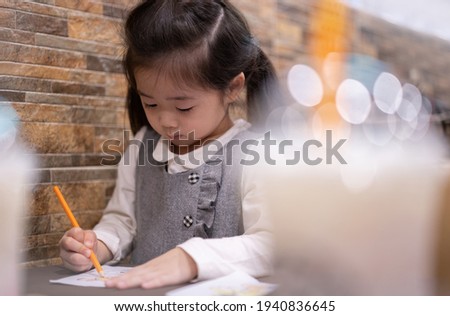 
Back to school. Happy smiling pupil drawing at the desk. Cute little preschooler child drawing at home. Kid girl drawing with pencils