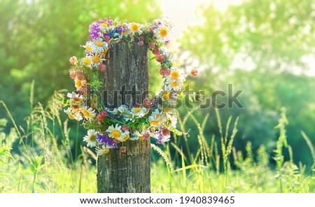 rustic wildflowers wreath on sunny meadow. Summer Solstice Day, Midsummer concept. floral traditional decor. pagan witch traditions, wiccan symbol and rituals Royalty-Free Stock Photo #1940839465