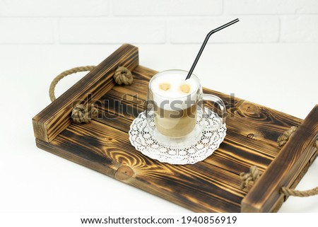 A cup of latte stands on a wooden tray for early breakfast