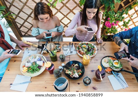 Young people taking food pictures with mobile smartphone to share on social media while having healthy meal in bar restaurant - Youth generation z and technology concept