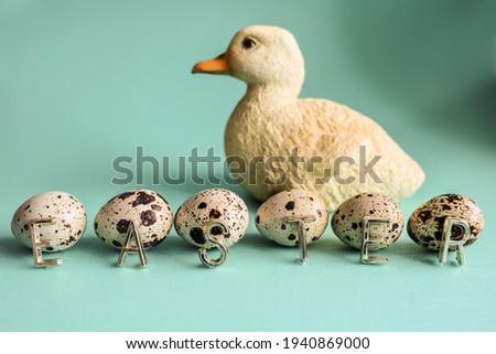 Happy Easter card lettering. Quail eggs with the sign saying "easter" with mint background and a yellow baby duck figure