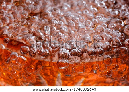 Abstract macro photography water in a powerful stream fills a red vase with the formation of air bubbles
