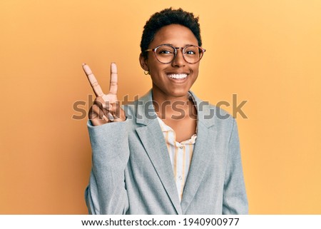 Young african american girl wearing business jacket and glasses showing and pointing up with fingers number two while smiling confident and happy. 