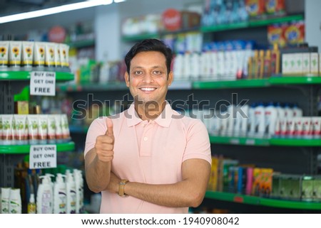 Happy young man show thumbs up at grocery store products. Royalty-Free Stock Photo #1940908042
